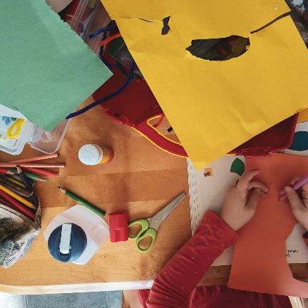 Bastelmaterial und Kinderhände auf einem Tisch in der Kindervilla
